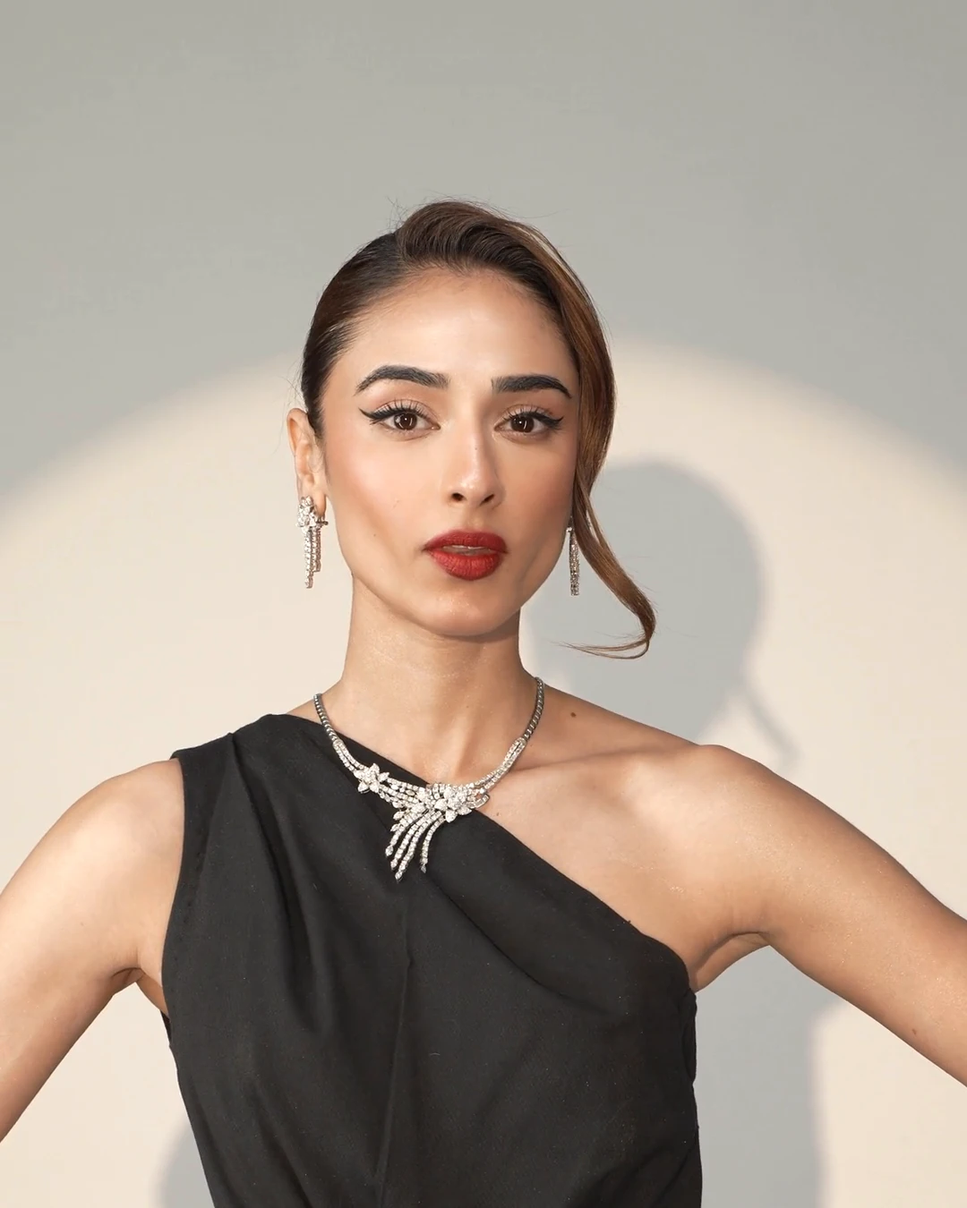 Una modelo con vestido negro de un hombro y joyas de tono plateado