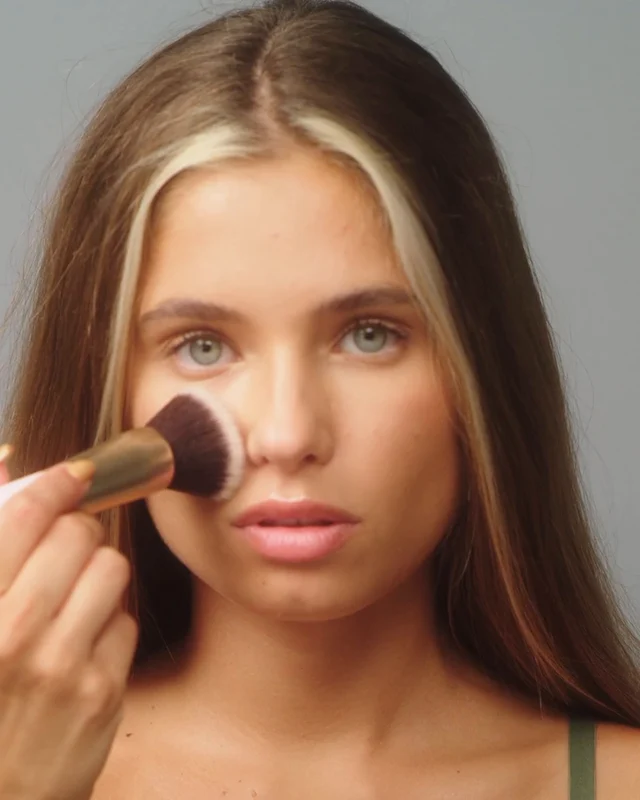 Una mujer aplicando maquillaje con una brocha