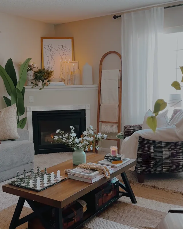 Un salón con chimenea, plantas y luz de ventana