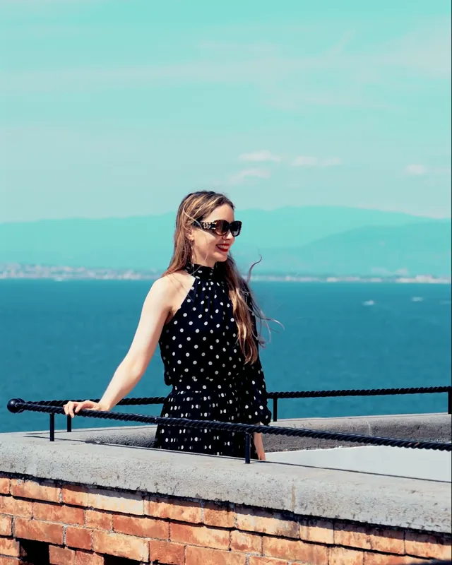 Una mujer con vestido oscuro en una terraza frente al mar