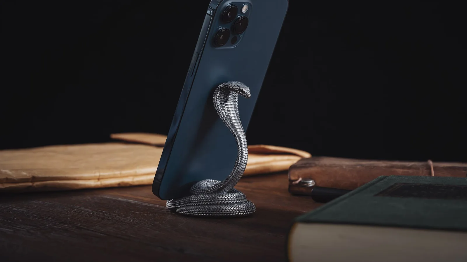 Móvil con funda oscura apoyado mediante un accesorio trasero sobre una mesa