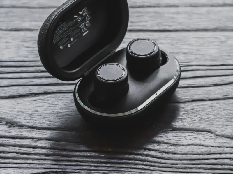 Auriculares pequeños dentro de un estuche negro abierto sobre madera