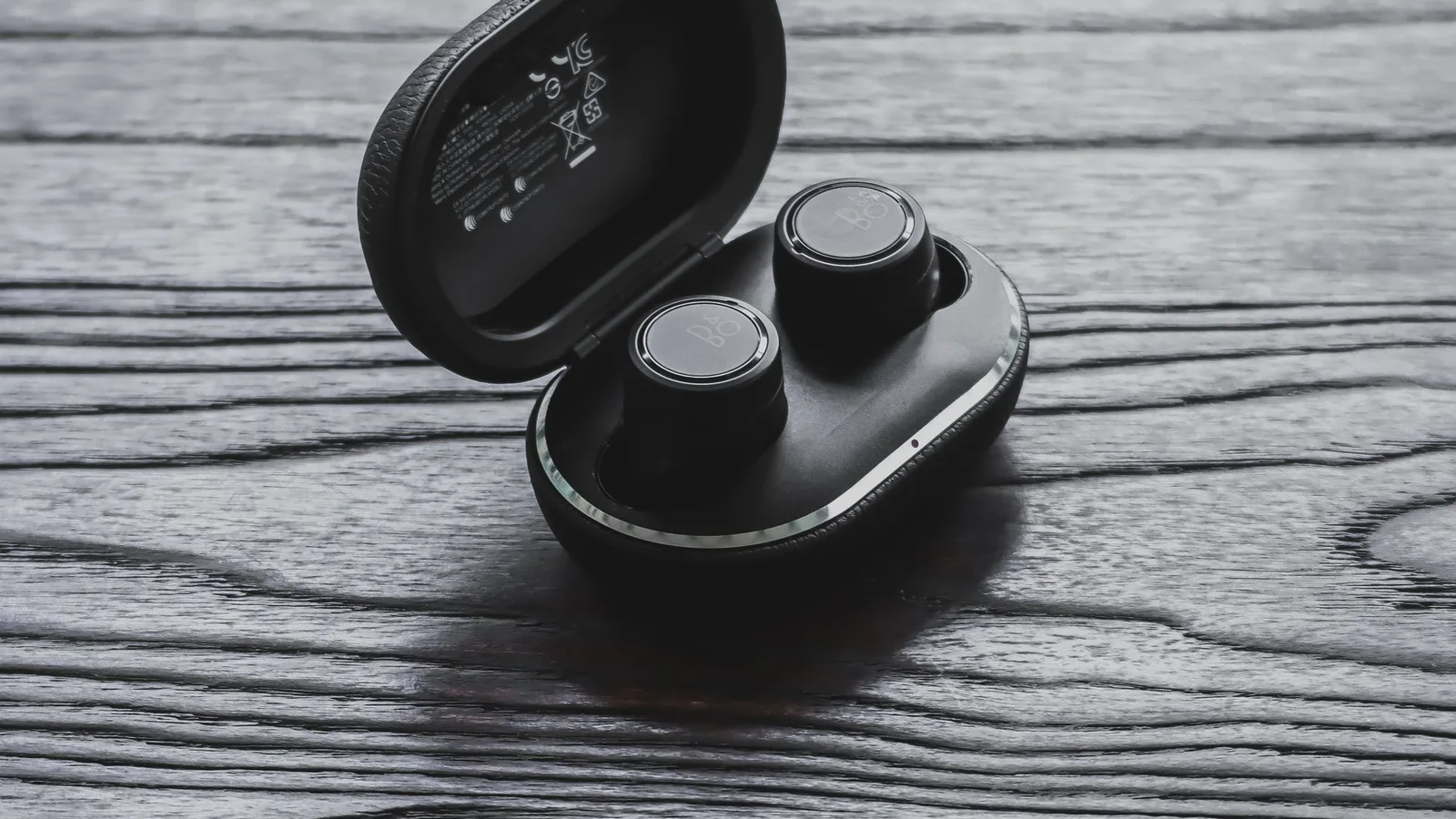 Auriculares pequeños dentro de un estuche negro abierto sobre madera