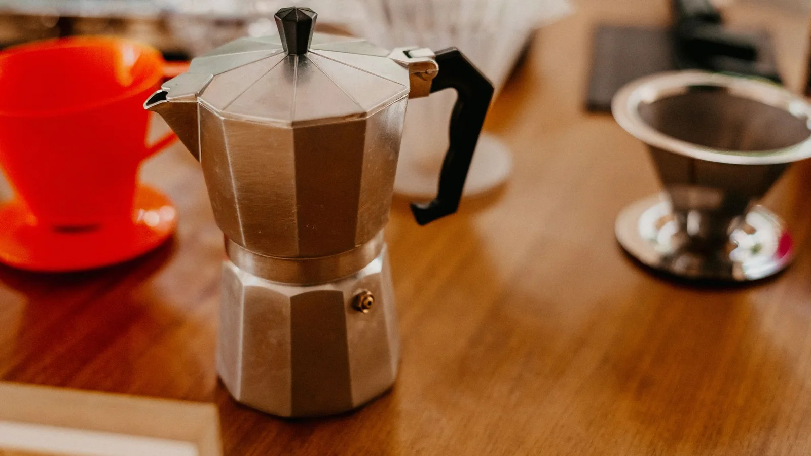 Cafetera sobre una mesa de madera junto a varias tazas