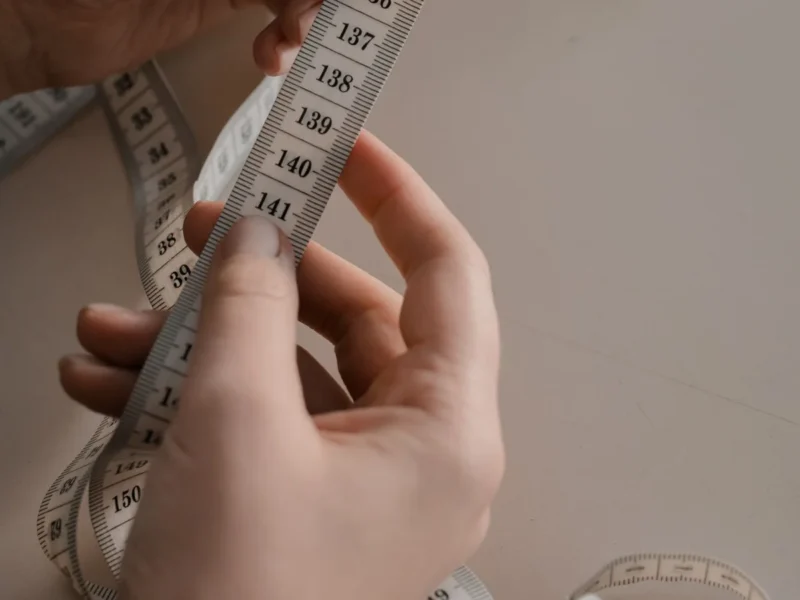 Manos sosteniendo una cinta métrica flexible de confección