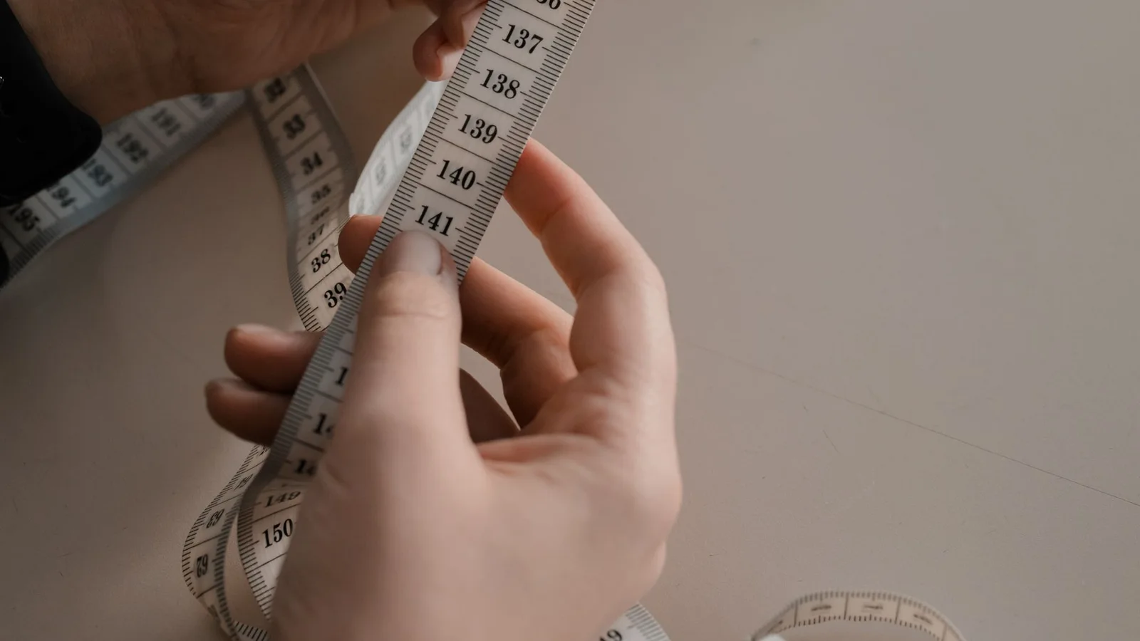 Manos sosteniendo una cinta métrica flexible de confección