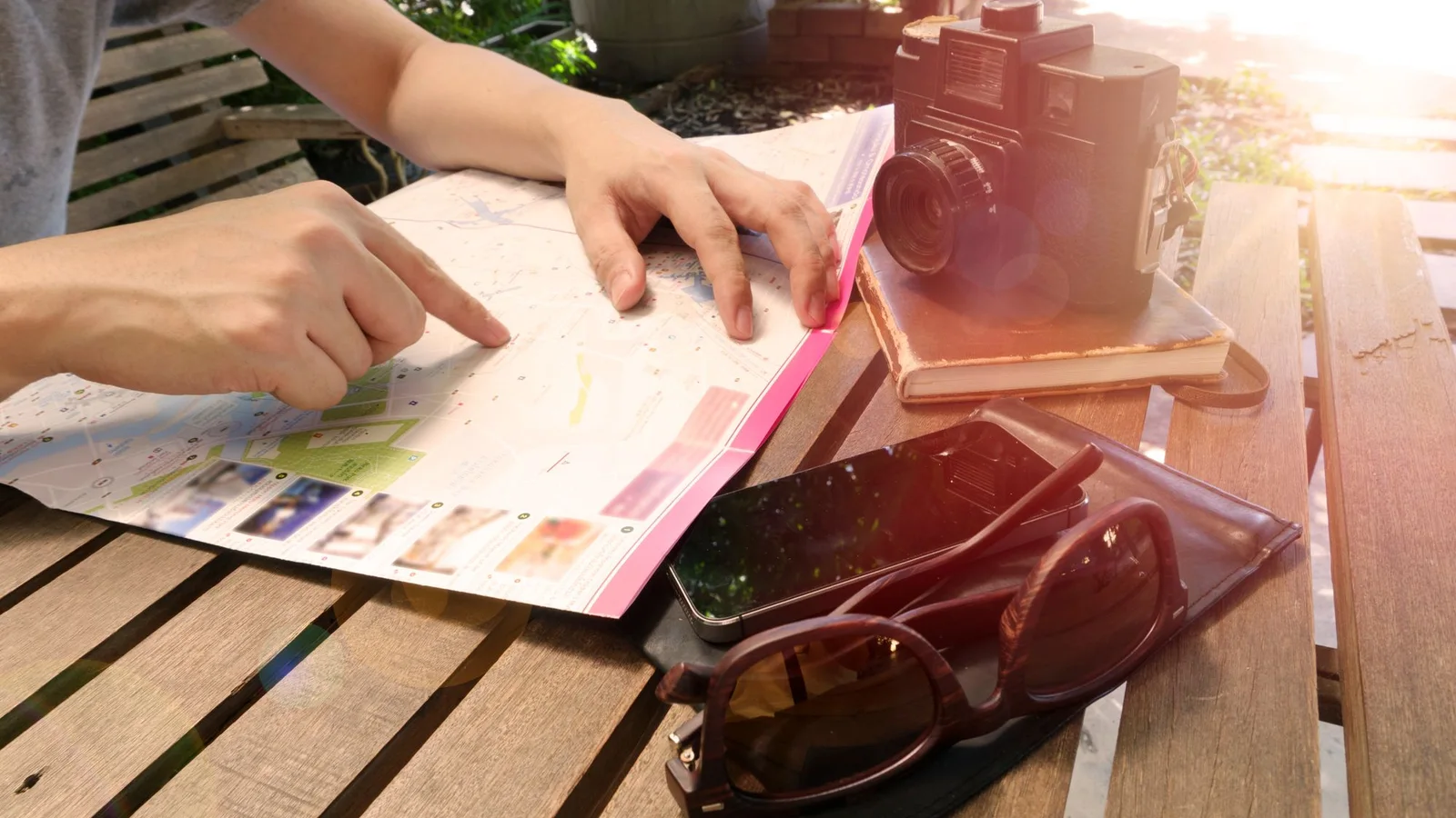 Manos señalando un mapa en una mesa junto a una cámara