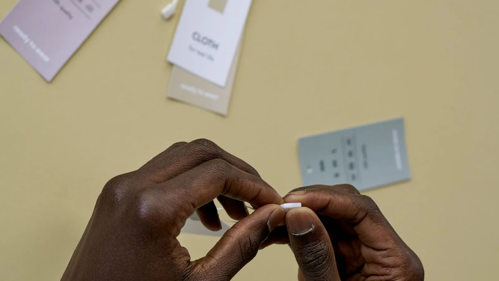 Etiquetas textiles y manos revisando información de prendas sobre una mesa