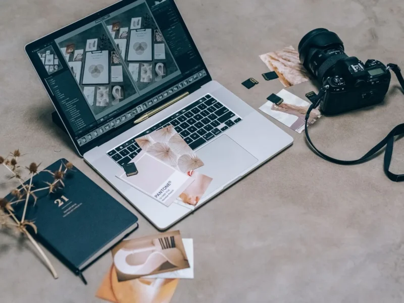 Ordenador con una cuadrícula de fotografías junto a una cámara y una libreta