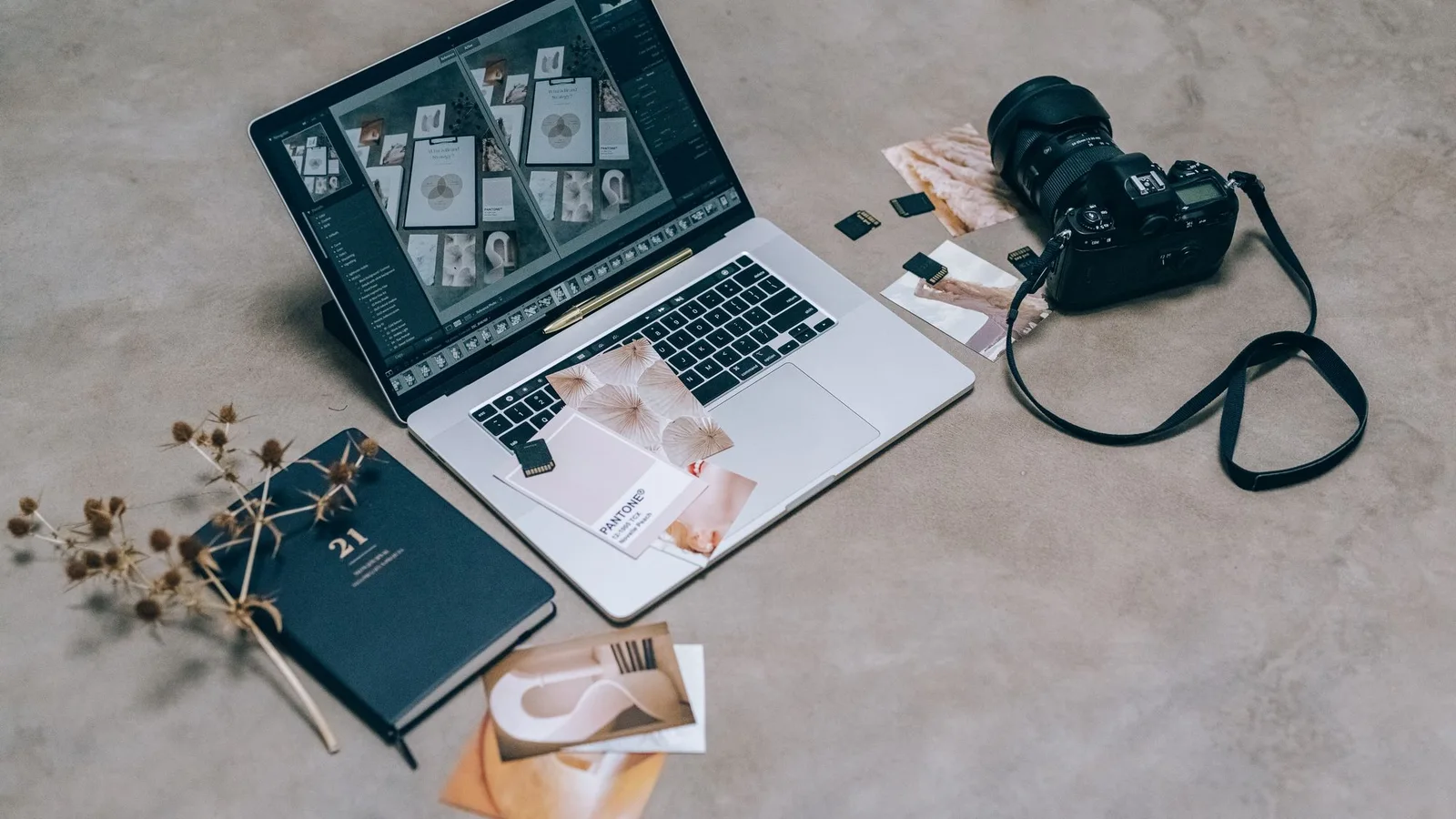 Ordenador con una cuadrícula de fotografías junto a una cámara y una libreta