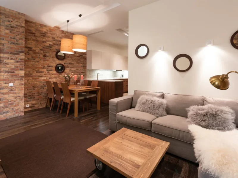 Salón con sofá, lámpara de pie y luminarias sobre la zona de comedor
