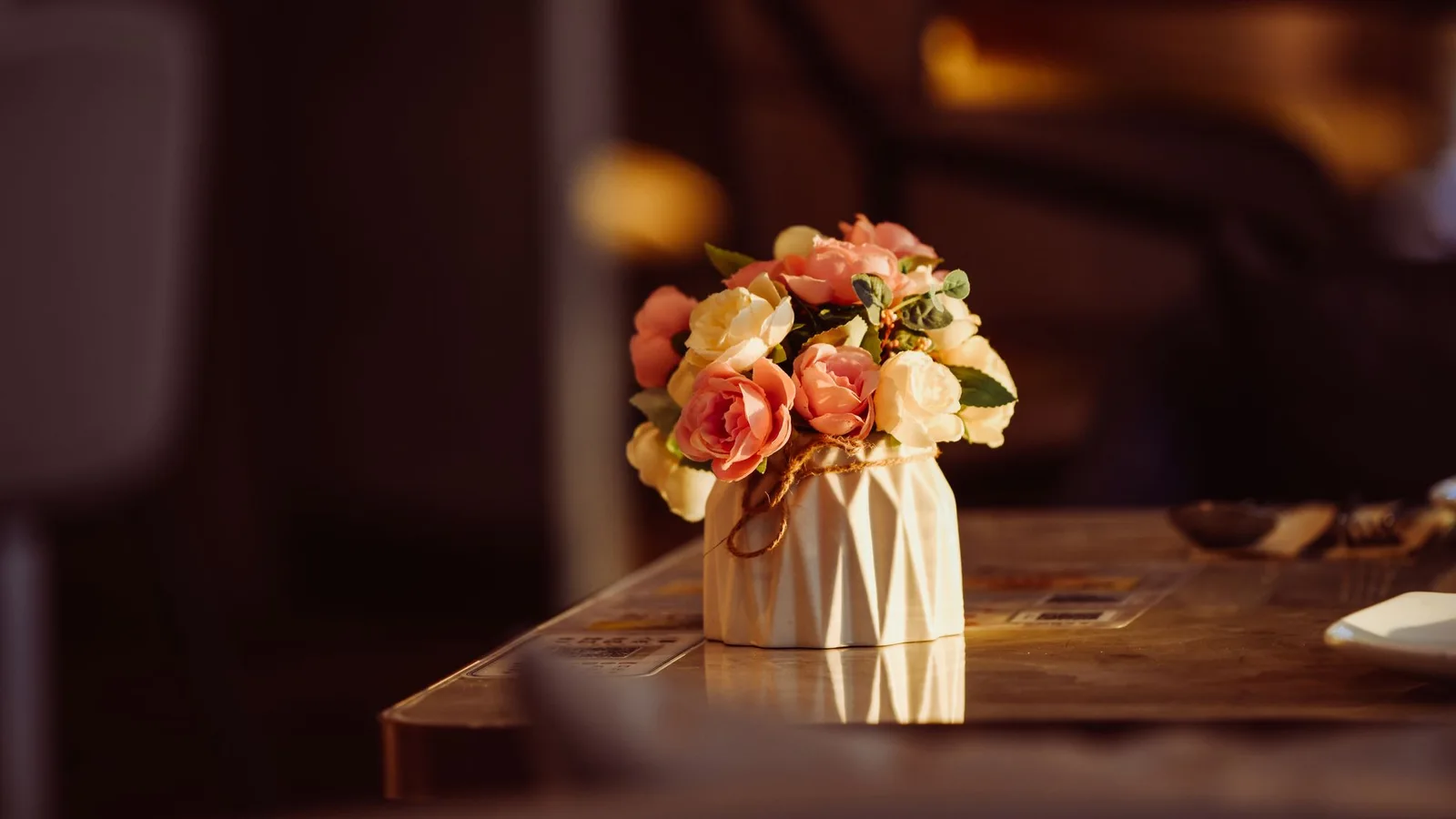 Ramo pequeño de flores rosadas y anaranjadas en un jarrón sobre una mesa