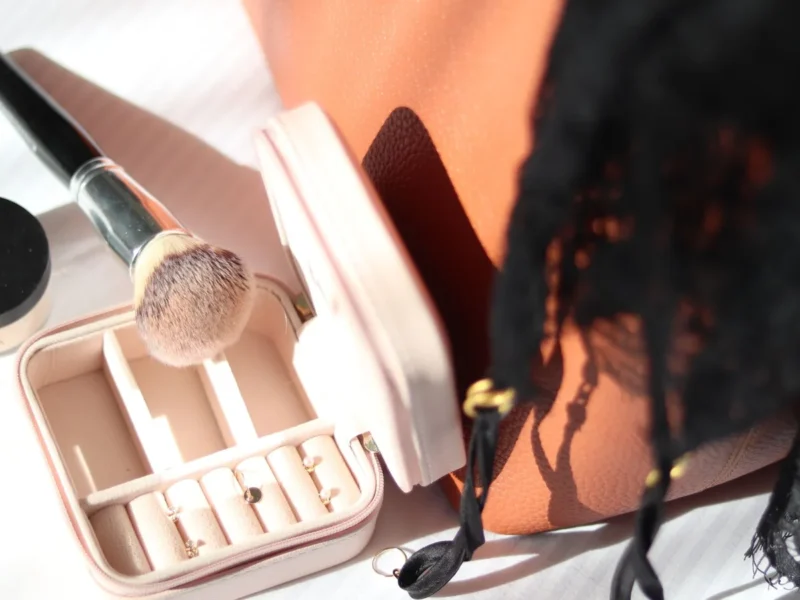 Joyero pequeño con pendientes separados, junto a una brocha y otros accesorios