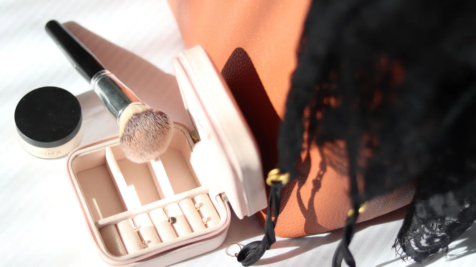 Joyero pequeño con pendientes separados, junto a una brocha y otros accesorios
