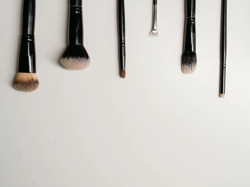 Brochas de maquillaje de distintas formas dispuestas sobre una superficie blanca.