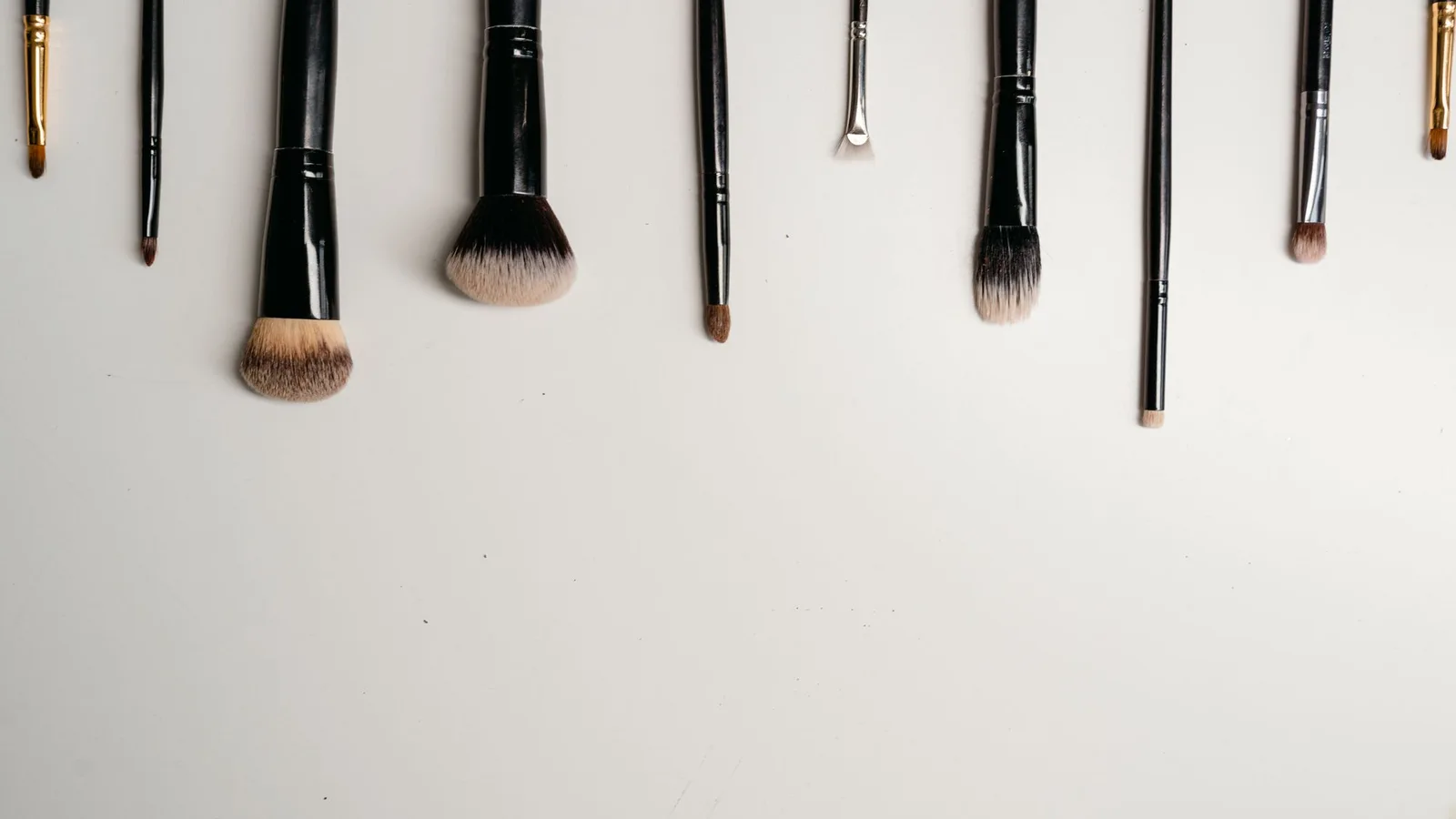 Brochas de maquillaje de distintas formas dispuestas sobre una superficie blanca.