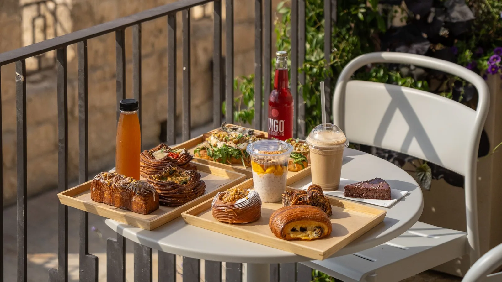 Mesa de desayuno junto a una barandilla con edificios y vegetación al fondo