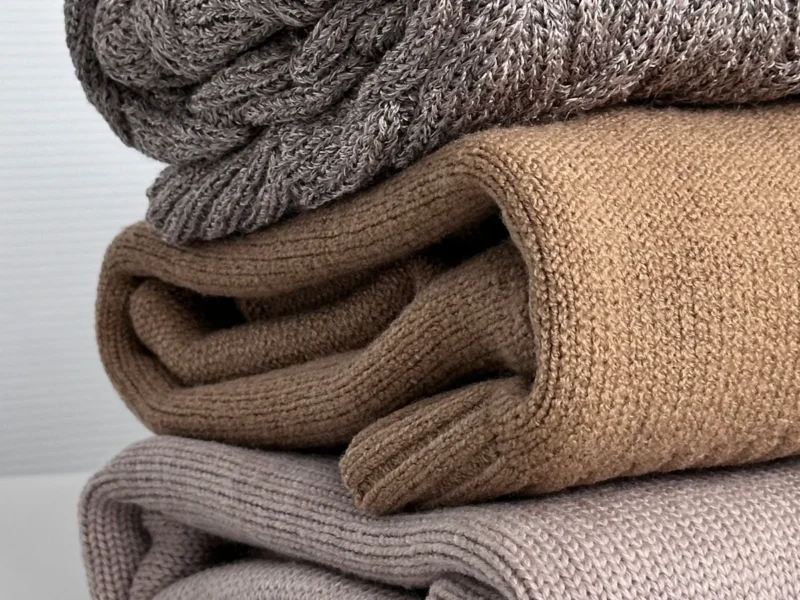 Textiles de punto doblados en tonos gris, camel y beige