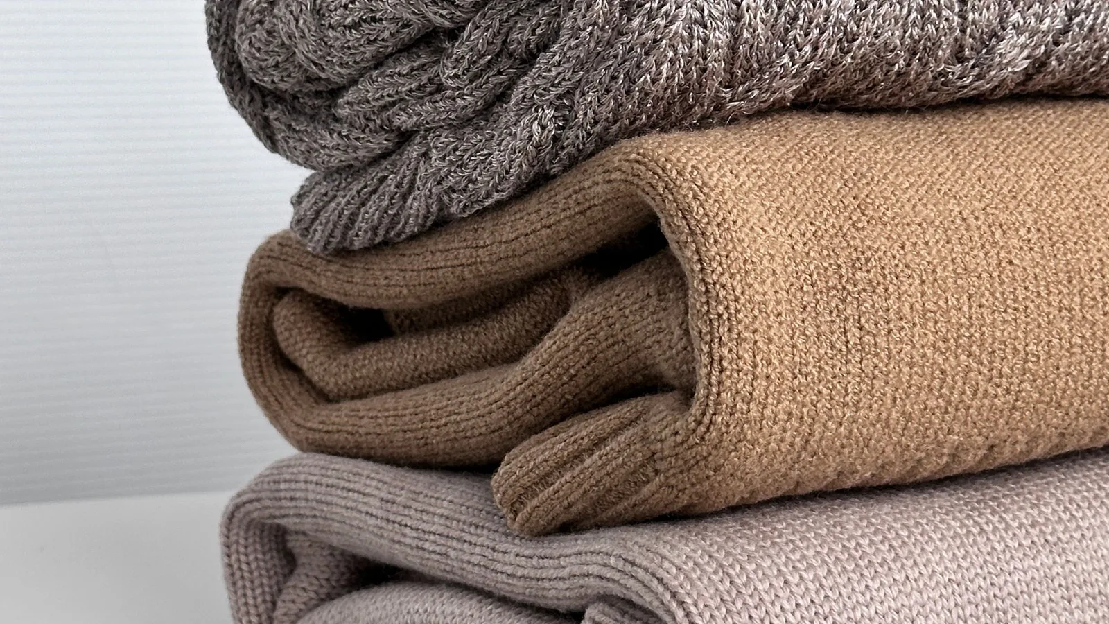 Textiles de punto doblados en tonos gris, camel y beige