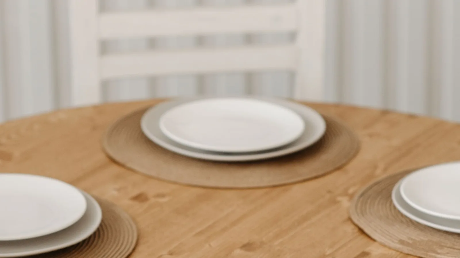 Plato blanco sobre un individual en una mesa de madera