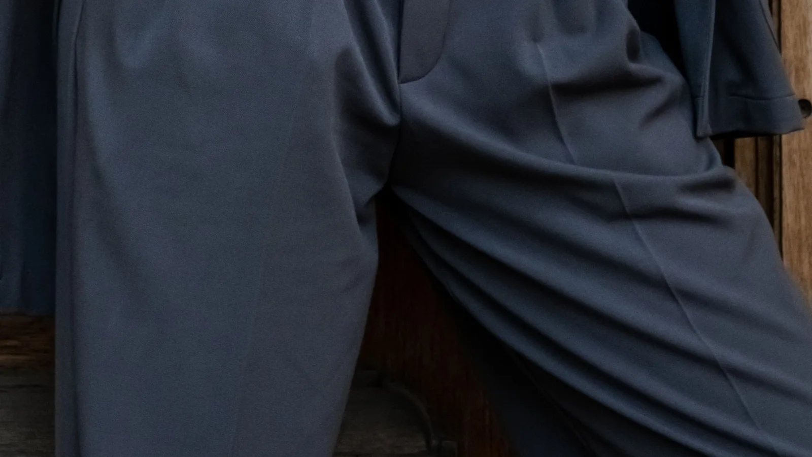 Detalle de la cintura, cinturón y pinzas de un pantalón gris