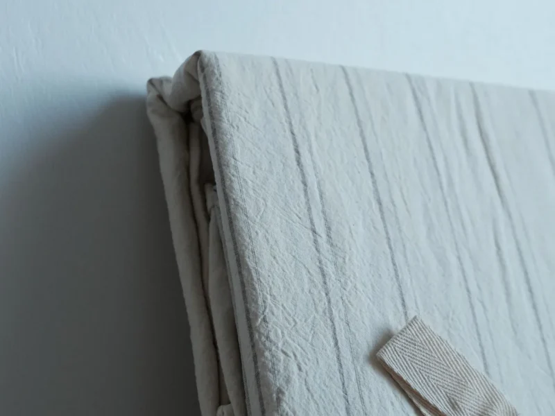 Ropa de cama clara doblada con la textura del tejido visible