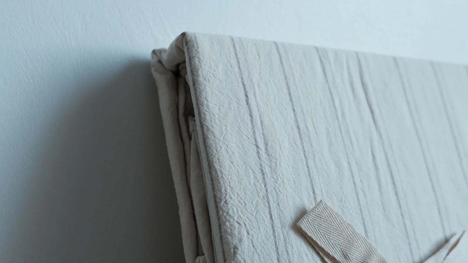 Ropa de cama clara doblada con la textura del tejido visible