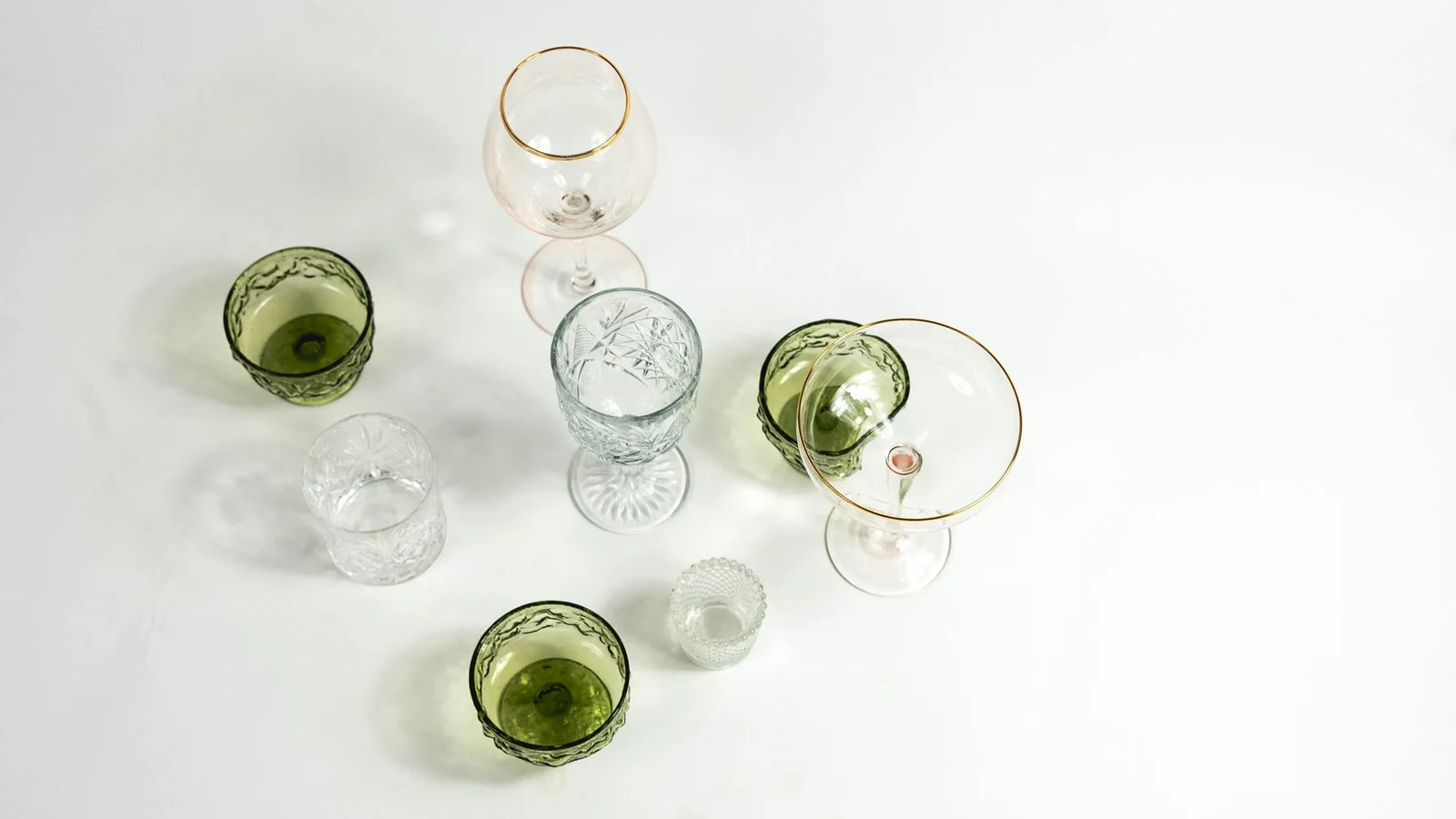 Vasos y copas transparentes y verdes de distintas formas vistos desde arriba