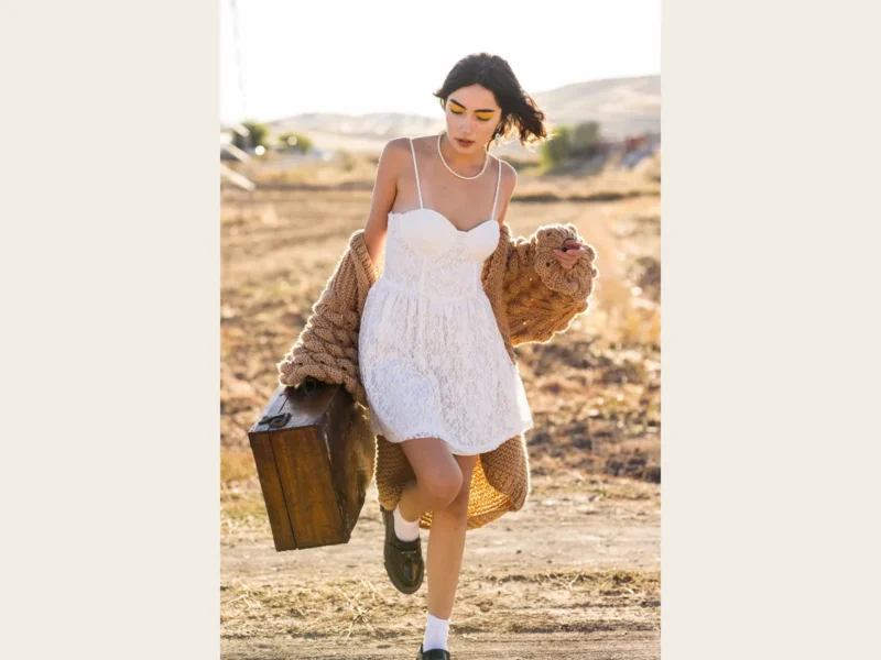 Vestido blanco combinado con una chaqueta de punto marrón al aire libre