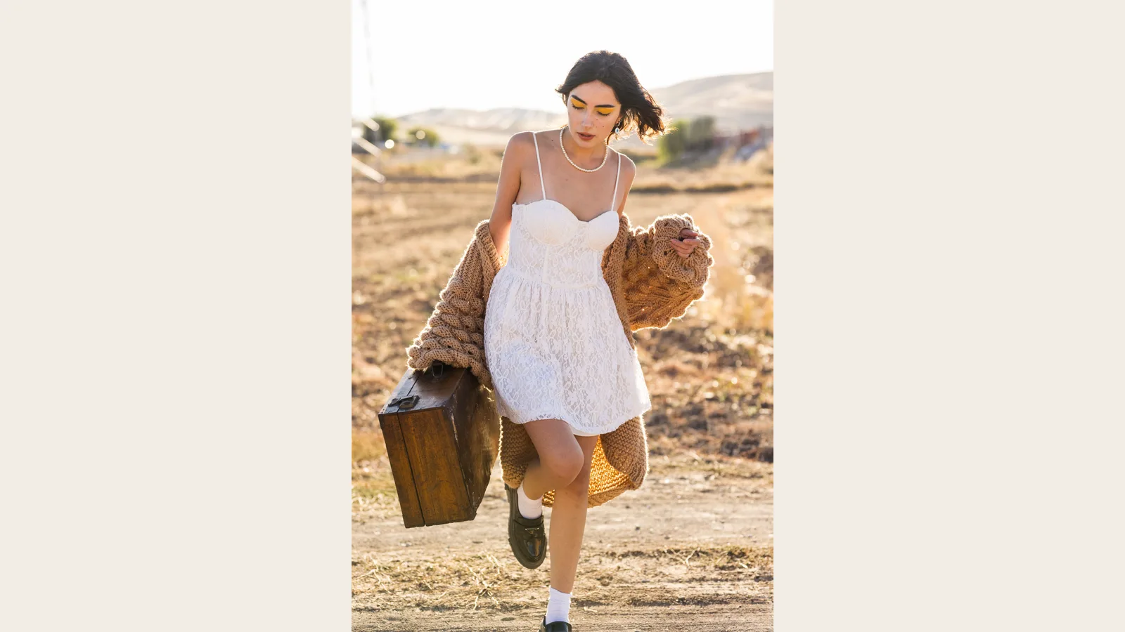 Vestido blanco combinado con una chaqueta de punto marrón al aire libre
